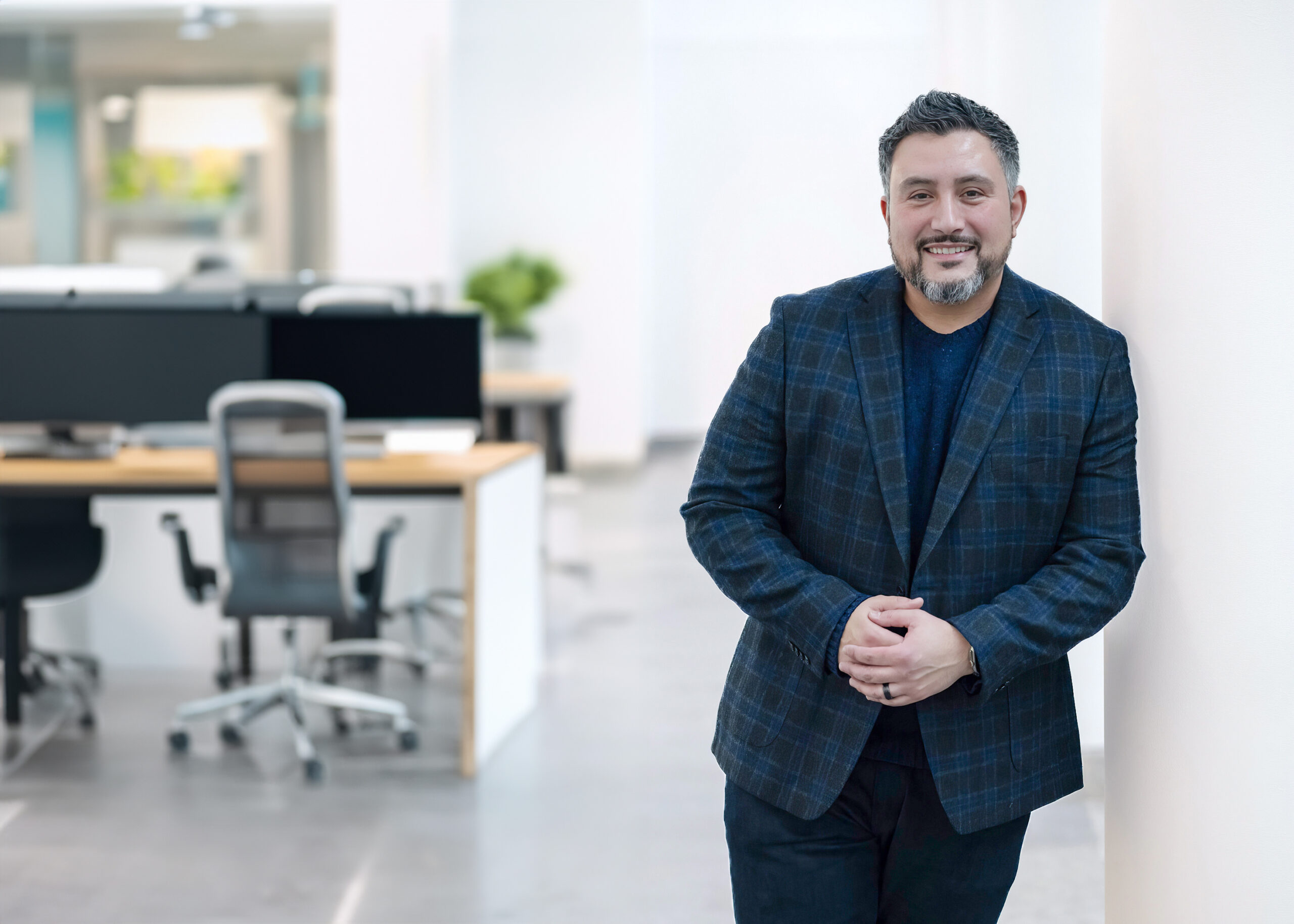 Personal Brand - Male in blue jacket leaning against a white column in a modern office